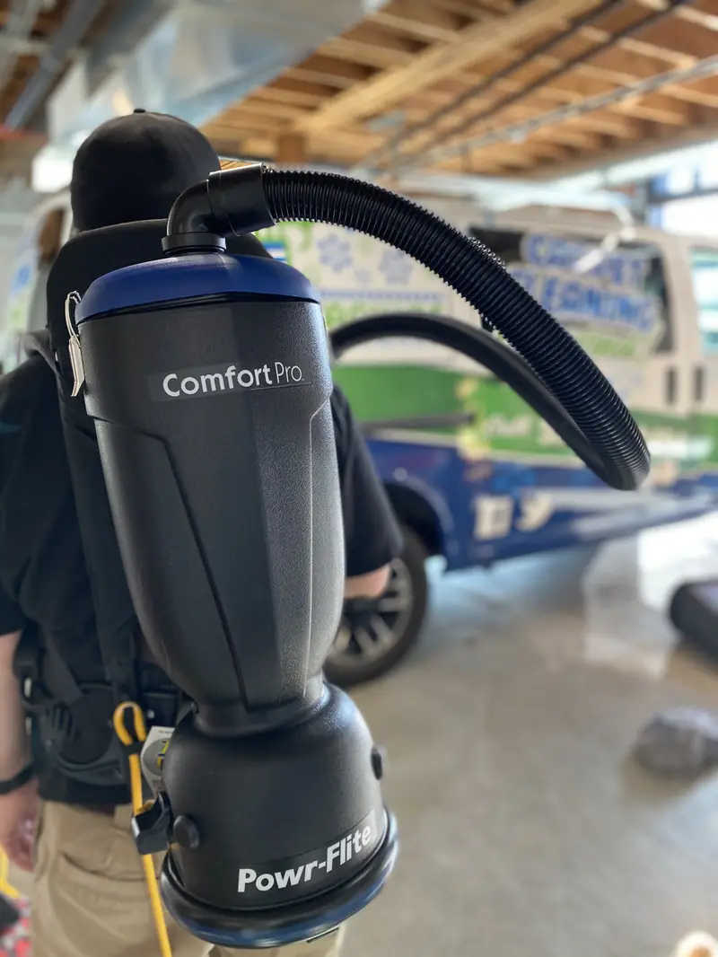 A backpack vacuum being put on in the shop