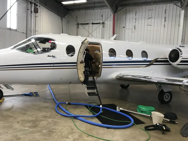 Hoses running up the steps into a private jet in a hangar