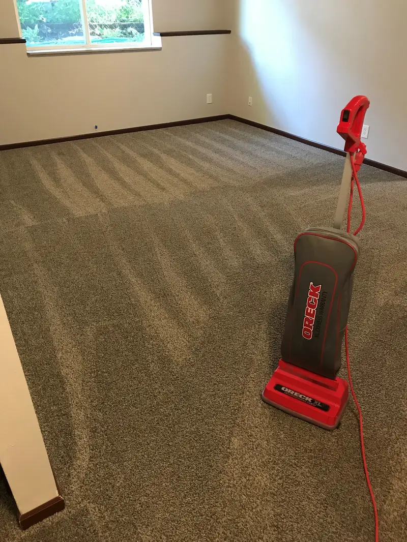 A red Oreck upright vacuum standing on a freshly cleaned carpet