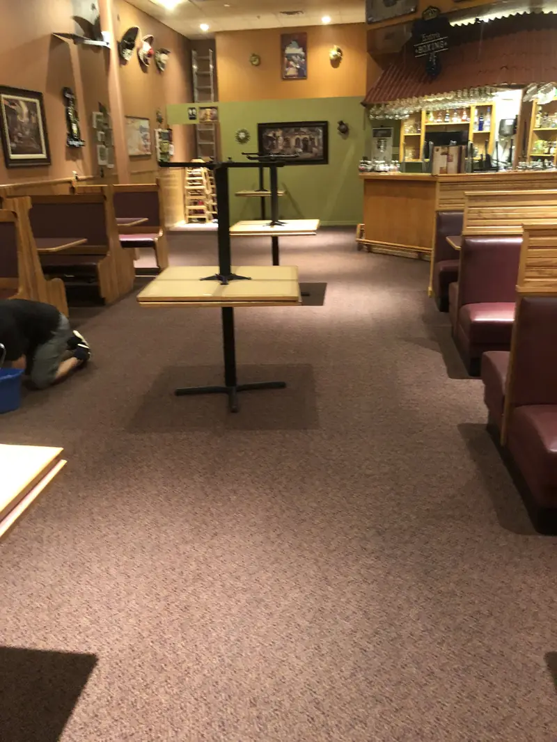 A restaurant dining room with its carpet being cleaned, tables lifted