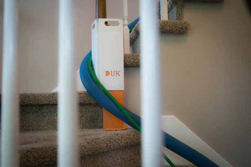 Hoses running up a carpeted staircase past a corner guard