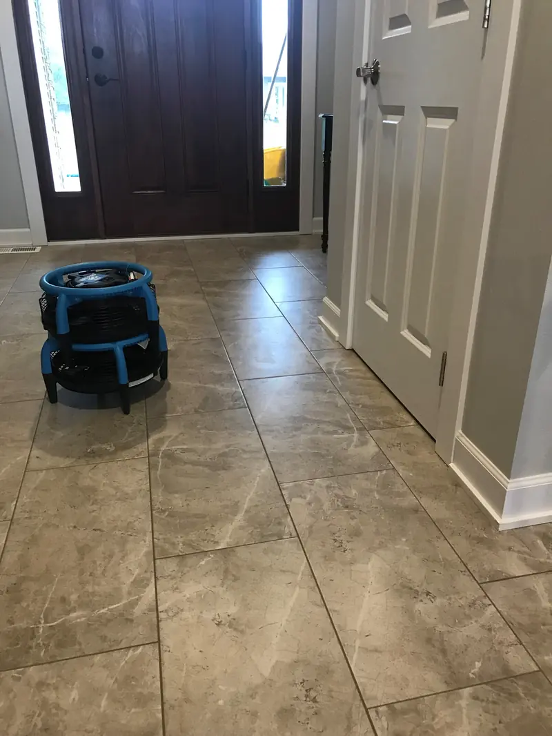 A tiled entryway drying under a blue fan