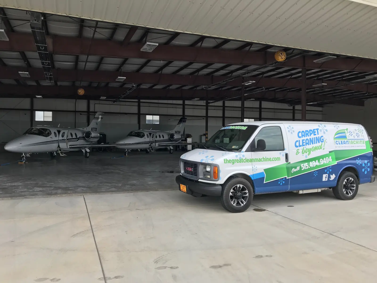 The Clean Machine van inside an aircraft hangar beside two private jets