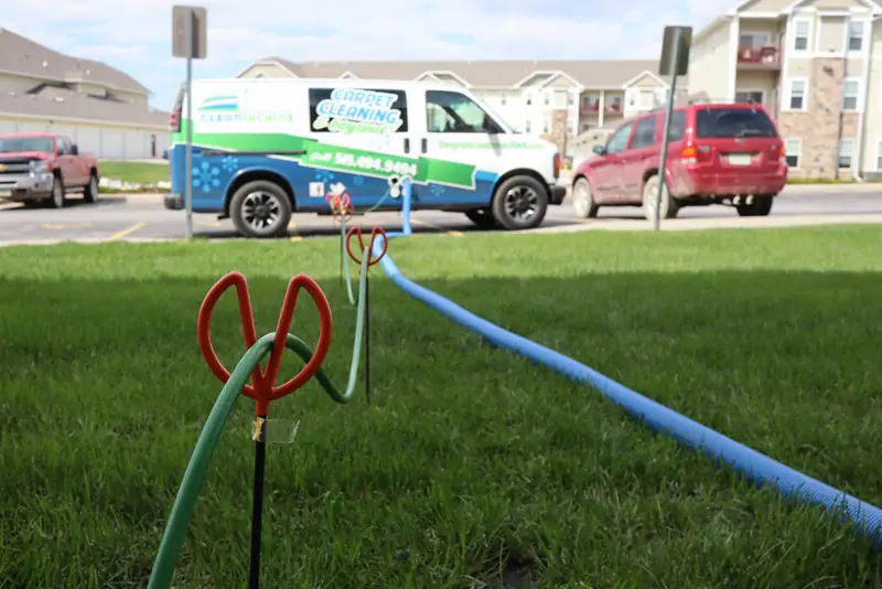 The van parked by an apartment building, hoses across the lawn